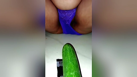 A brunette is sucking a cucumber at her feet to her pussy